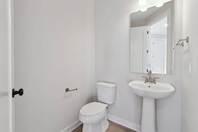 bathroom with a sink, toilet, baseboards, and wood finished floors