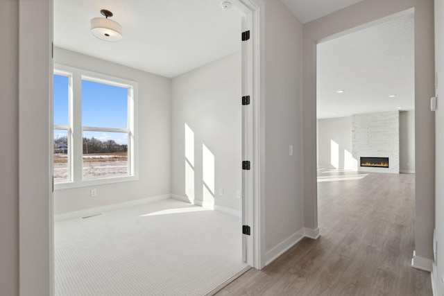 hallway featuring carpet flooring, visible vents, baseboards, and wood finished floors