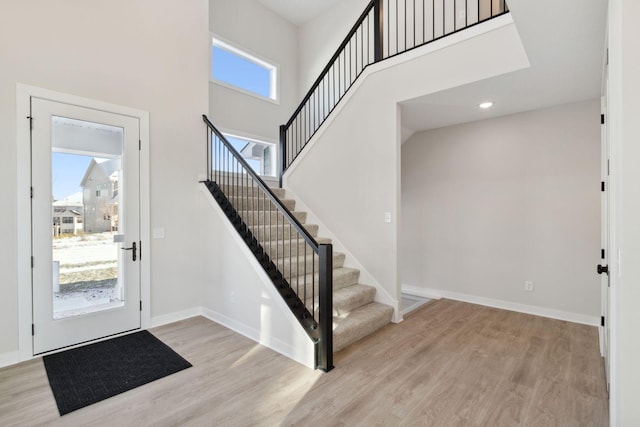 entrance foyer with stairs, a high ceiling, wood finished floors, and baseboards