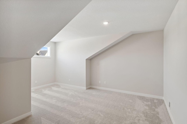 additional living space with lofted ceiling, a textured ceiling, carpet, and baseboards