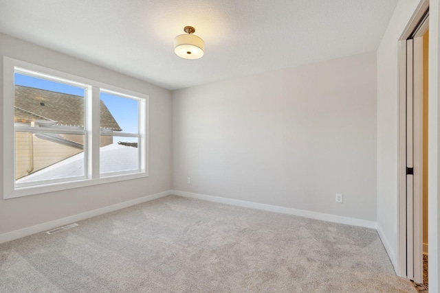 carpeted spare room featuring baseboards and visible vents