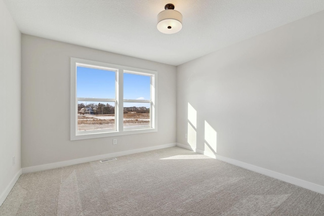 carpeted empty room with visible vents and baseboards