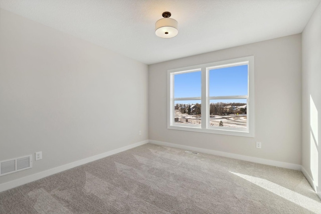 carpeted spare room with visible vents and baseboards