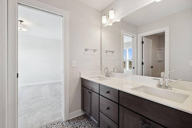 full bathroom with double vanity, baseboards, and a sink