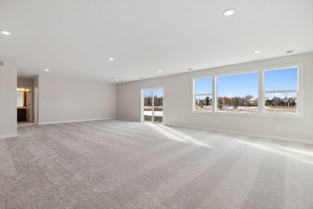 unfurnished living room featuring baseboards, recessed lighting, and light colored carpet