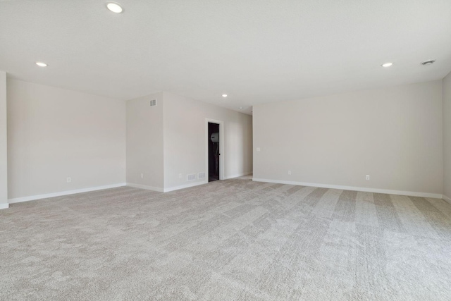 spare room with baseboards, light colored carpet, visible vents, and recessed lighting