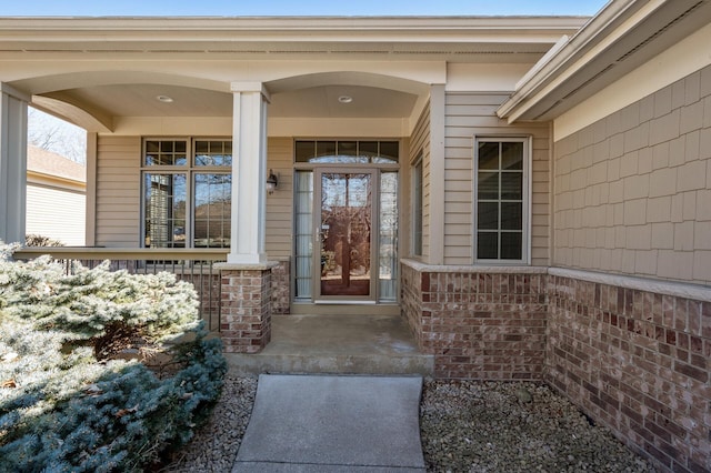 property entrance with a porch and brick siding