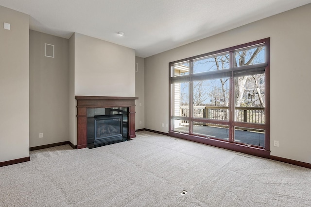 unfurnished living room with baseboards, a fireplace with flush hearth, visible vents, and carpet flooring