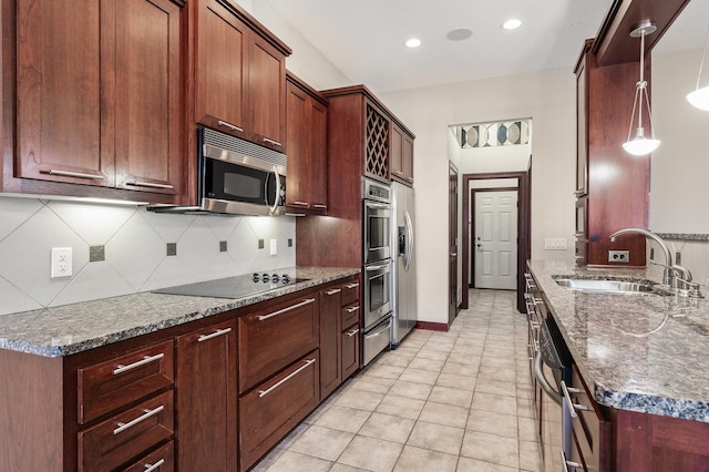 kitchen featuring dark stone counters, a sink, appliances with stainless steel finishes, a warming drawer, and tasteful backsplash