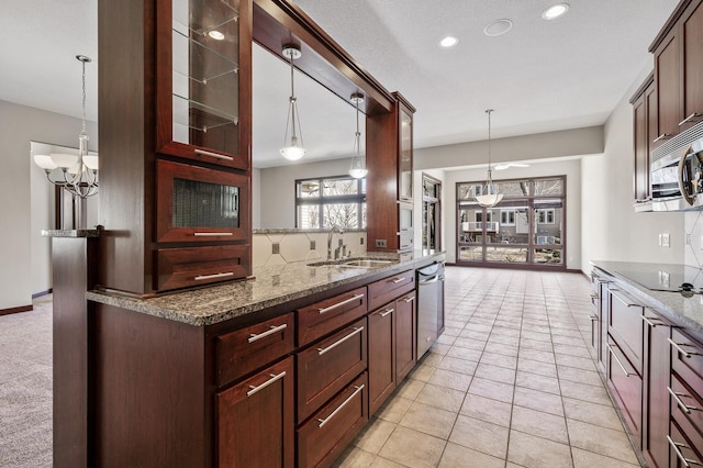 kitchen with tasteful backsplash, appliances with stainless steel finishes, dark stone counters, and a sink