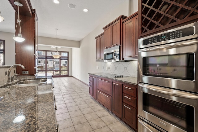 kitchen featuring tasteful backsplash, dark stone counters, light tile patterned floors, appliances with stainless steel finishes, and a sink