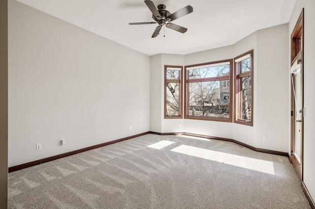 carpeted spare room with a ceiling fan and baseboards