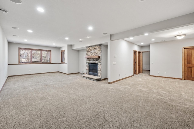 unfurnished living room featuring light carpet, a stone fireplace, recessed lighting, and baseboards