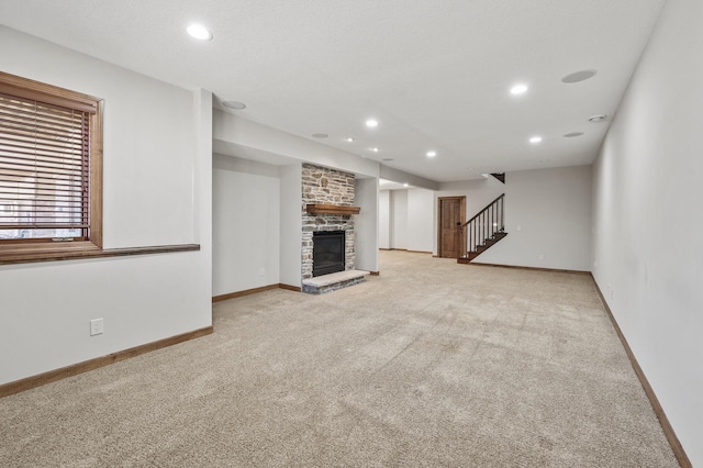 unfurnished living room with baseboards, light colored carpet, stairs, a stone fireplace, and recessed lighting