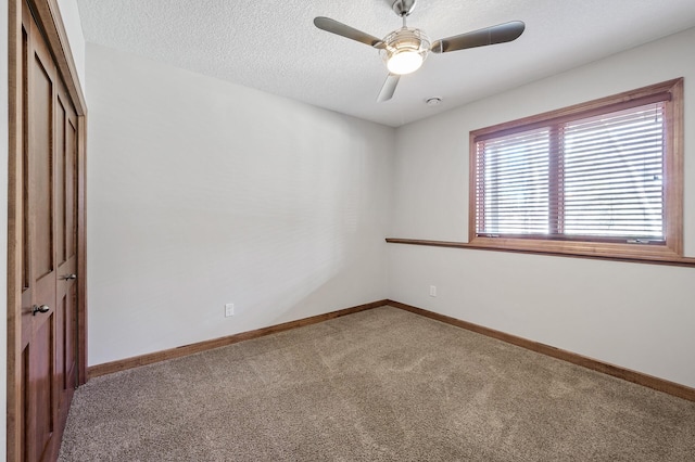 carpeted spare room with ceiling fan, baseboards, and a textured ceiling