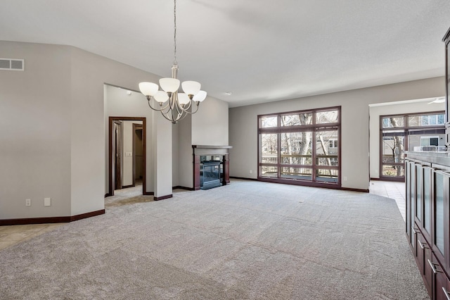 unfurnished living room featuring visible vents, baseboards, light carpet, an inviting chandelier, and a glass covered fireplace