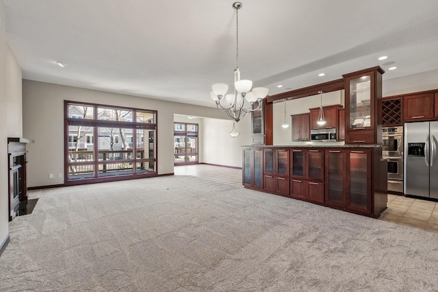 kitchen with light carpet, pendant lighting, stainless steel appliances, an inviting chandelier, and glass insert cabinets