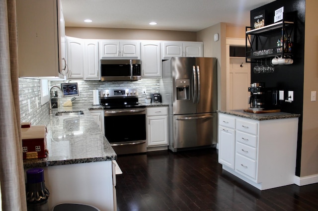 kitchen with appliances with stainless steel finishes, backsplash, stone countertops, and a sink