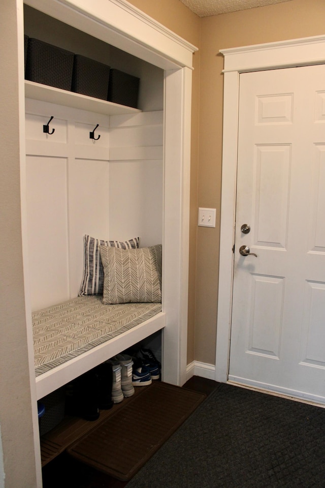 mudroom featuring a textured ceiling and baseboards