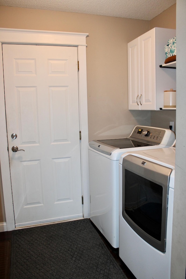 laundry room with a textured ceiling, washer and clothes dryer, and cabinet space