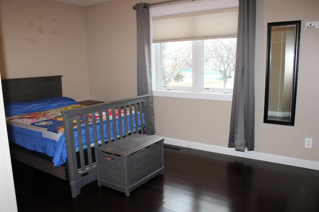 bedroom with dark wood-style floors, visible vents, and baseboards