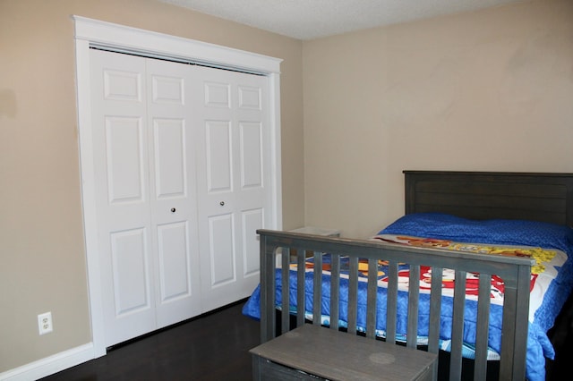 bedroom featuring dark wood-style floors, a closet, and baseboards