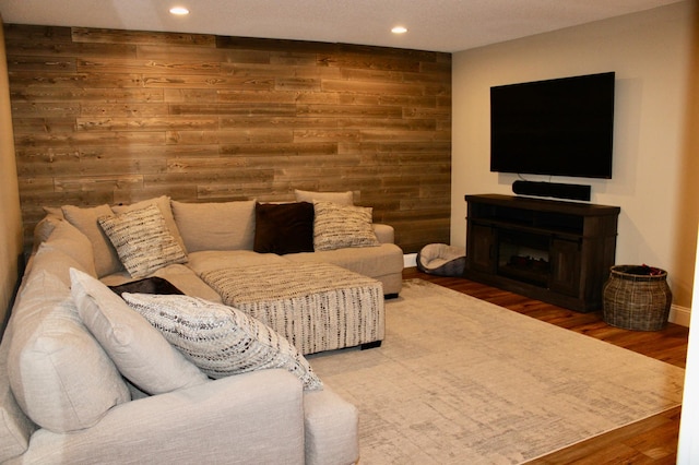 living room featuring recessed lighting, a fireplace, wooden walls, and wood finished floors