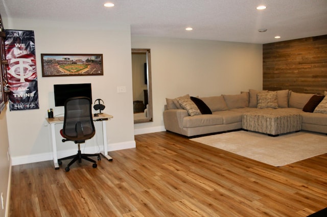 living room with light wood-type flooring, wood walls, baseboards, and recessed lighting