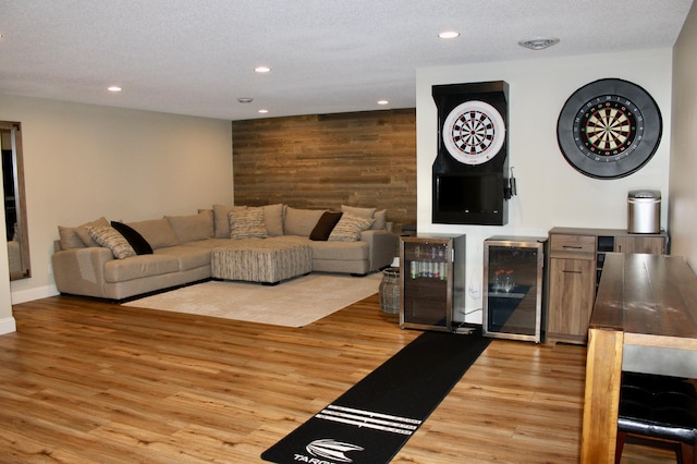 living room featuring recessed lighting, beverage cooler, wood walls, and wood finished floors