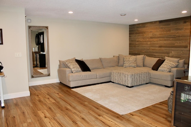 living room with wood walls, wood finished floors, and recessed lighting