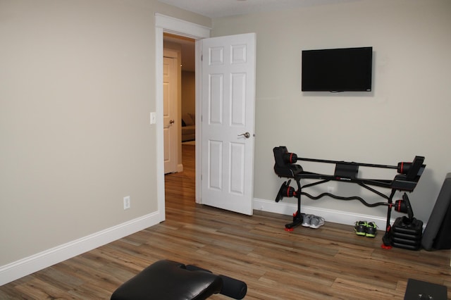 workout room featuring baseboards and wood finished floors