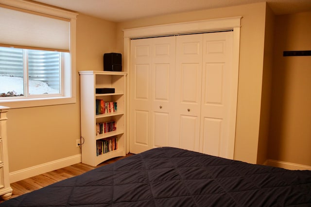 bedroom featuring a closet, wood finished floors, and baseboards