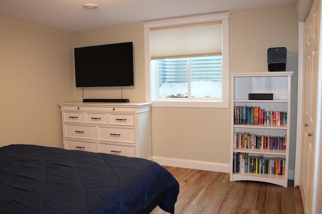 bedroom with light wood finished floors and baseboards