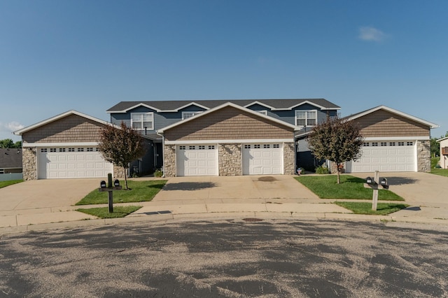 view of front of home with a garage, stone siding, and driveway