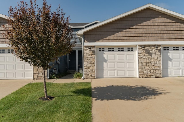 view of front of property featuring concrete driveway, a front lawn, and stone siding