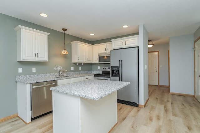 kitchen with stainless steel appliances, a sink, white cabinets, hanging light fixtures, and light wood-type flooring