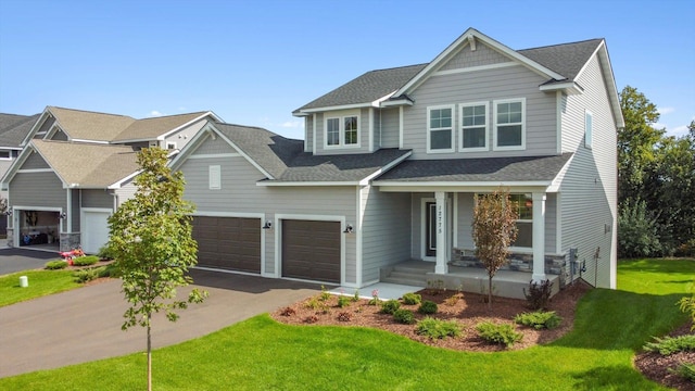 craftsman-style home featuring a porch, aphalt driveway, an attached garage, roof with shingles, and a front lawn