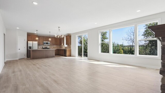 unfurnished living room with recessed lighting, a notable chandelier, and light wood finished floors