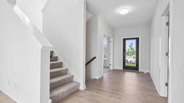 entrance foyer with stairway, baseboards, and wood finished floors