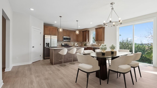 dining area with baseboards, light wood-type flooring, a notable chandelier, and recessed lighting