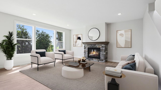 living area with recessed lighting, baseboards, wood finished floors, and a stone fireplace