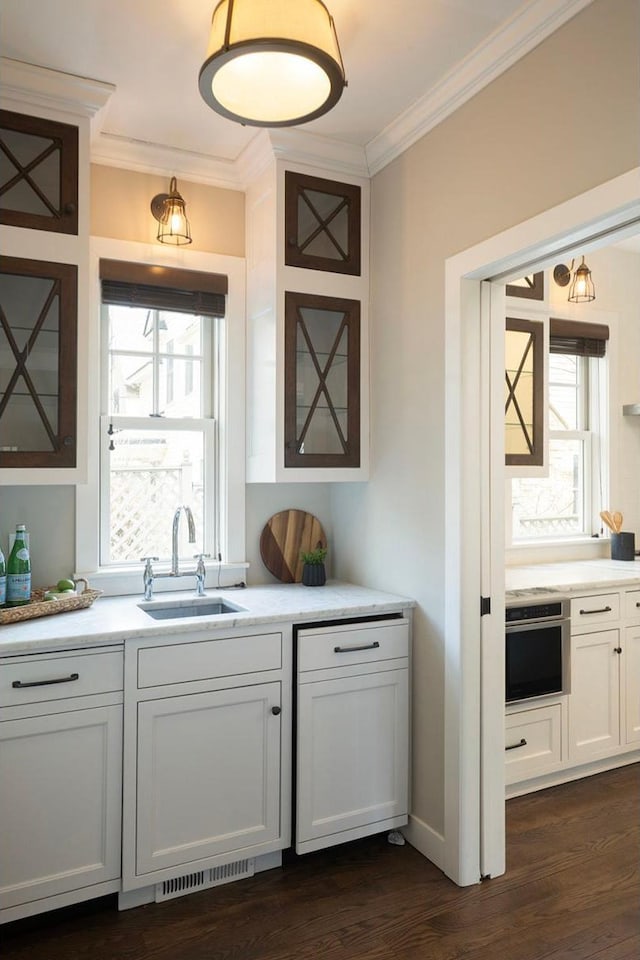 bar featuring a sink, oven, crown molding, and dark wood-style floors