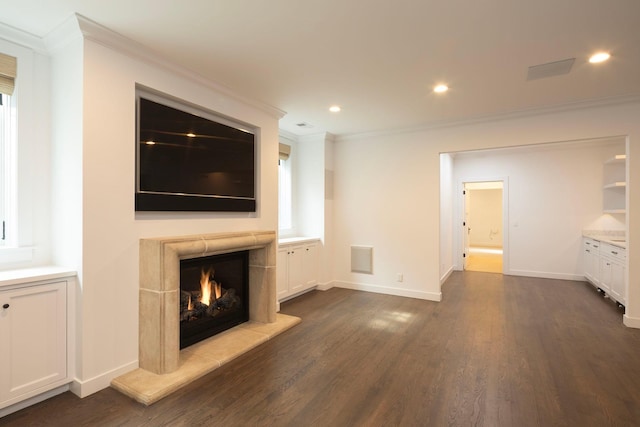 unfurnished living room featuring ornamental molding, dark wood-style flooring, a warm lit fireplace, baseboards, and recessed lighting