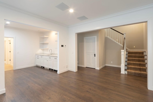 unfurnished living room with stairs, dark wood-style floors, ornamental molding, a sink, and baseboards