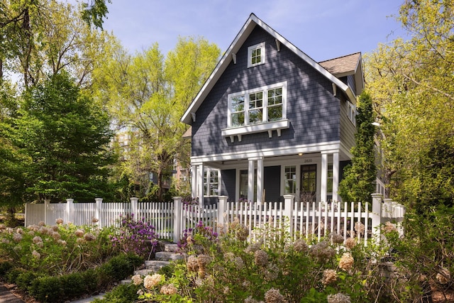 shingle-style home with a fenced front yard and a porch