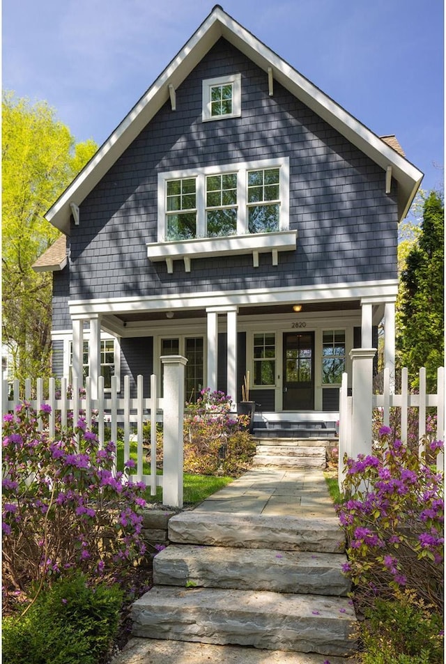 rear view of house featuring covered porch and fence