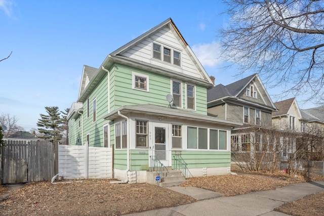 traditional style home featuring a sunroom and fence