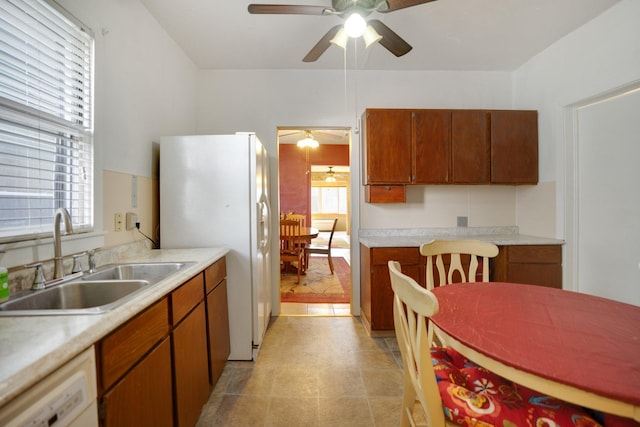 kitchen featuring a sink, brown cabinets, white appliances, and light countertops