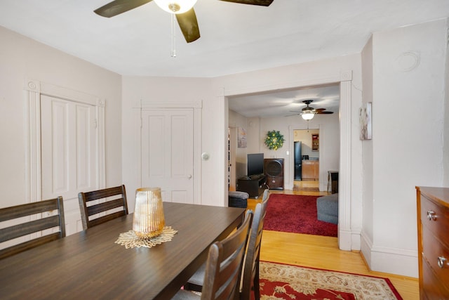 dining space featuring a ceiling fan, baseboards, and light wood-type flooring