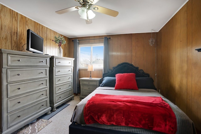 bedroom featuring light carpet, wood walls, and ceiling fan